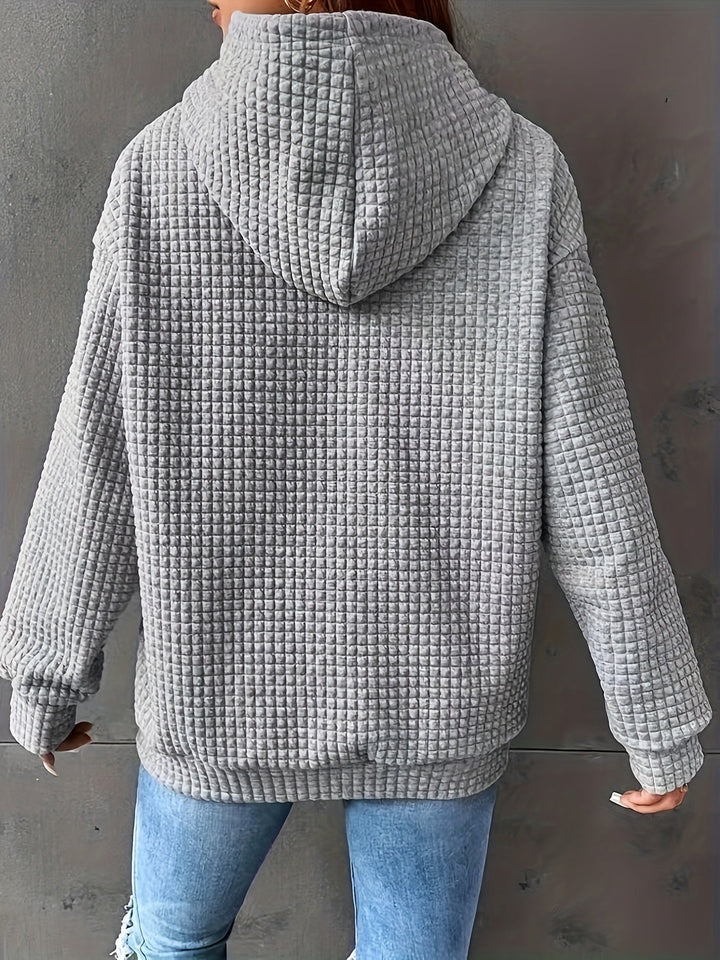 Dettaglio texture unica su felpa donna con cappuccio e tasca marsupio. Stile abbigliamento casual.
