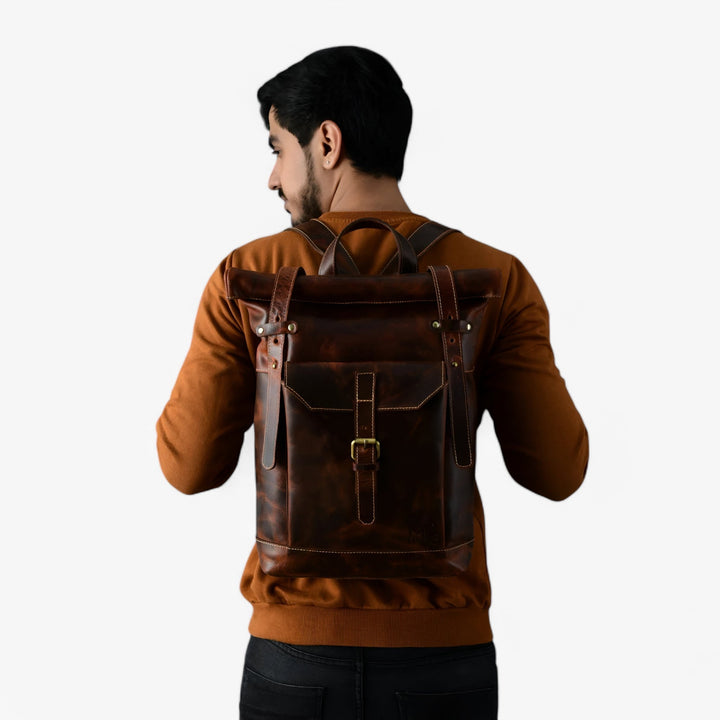 Zaino roll top marrone indossato, mostra l'adattabilità e lo stile unisex. Ideale per la vita urbana.
