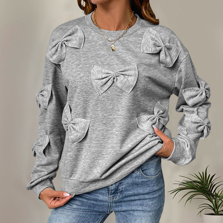Moda invernale: maglia donna morbida grigia con nodo decorativo. Girocollo casual a maniche lunghe.