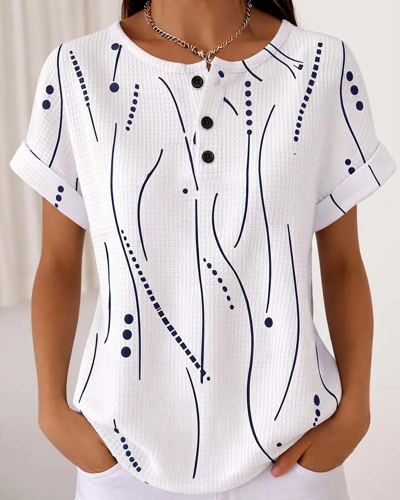 T-shirt donna casual con stampa grafica e bottoni decorativi. Ideale per outfit quotidiani primavera estate.