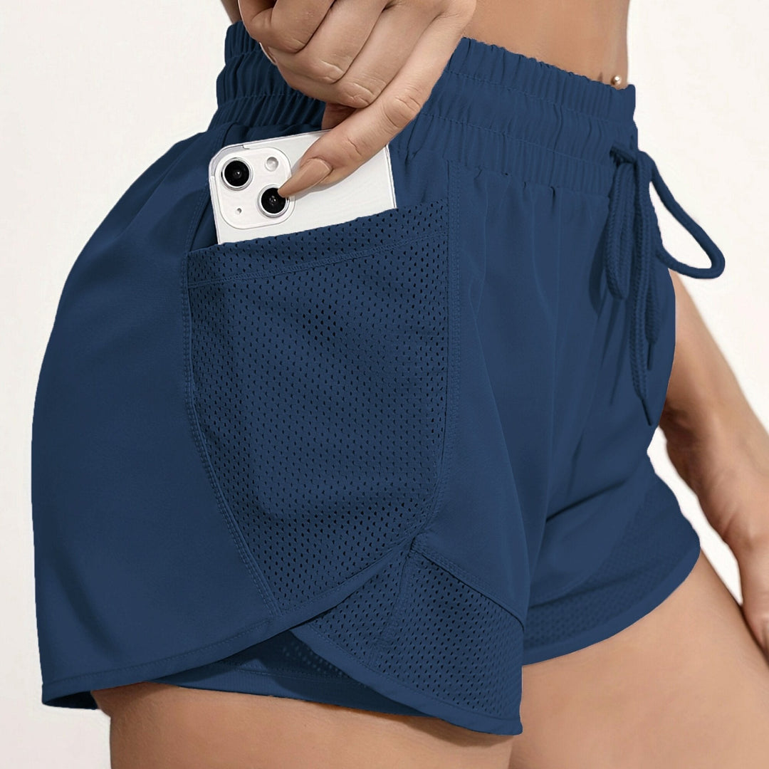 Donna che corre indossando pantaloncini sportivi neri per allenamento, massima libertà di movimento.