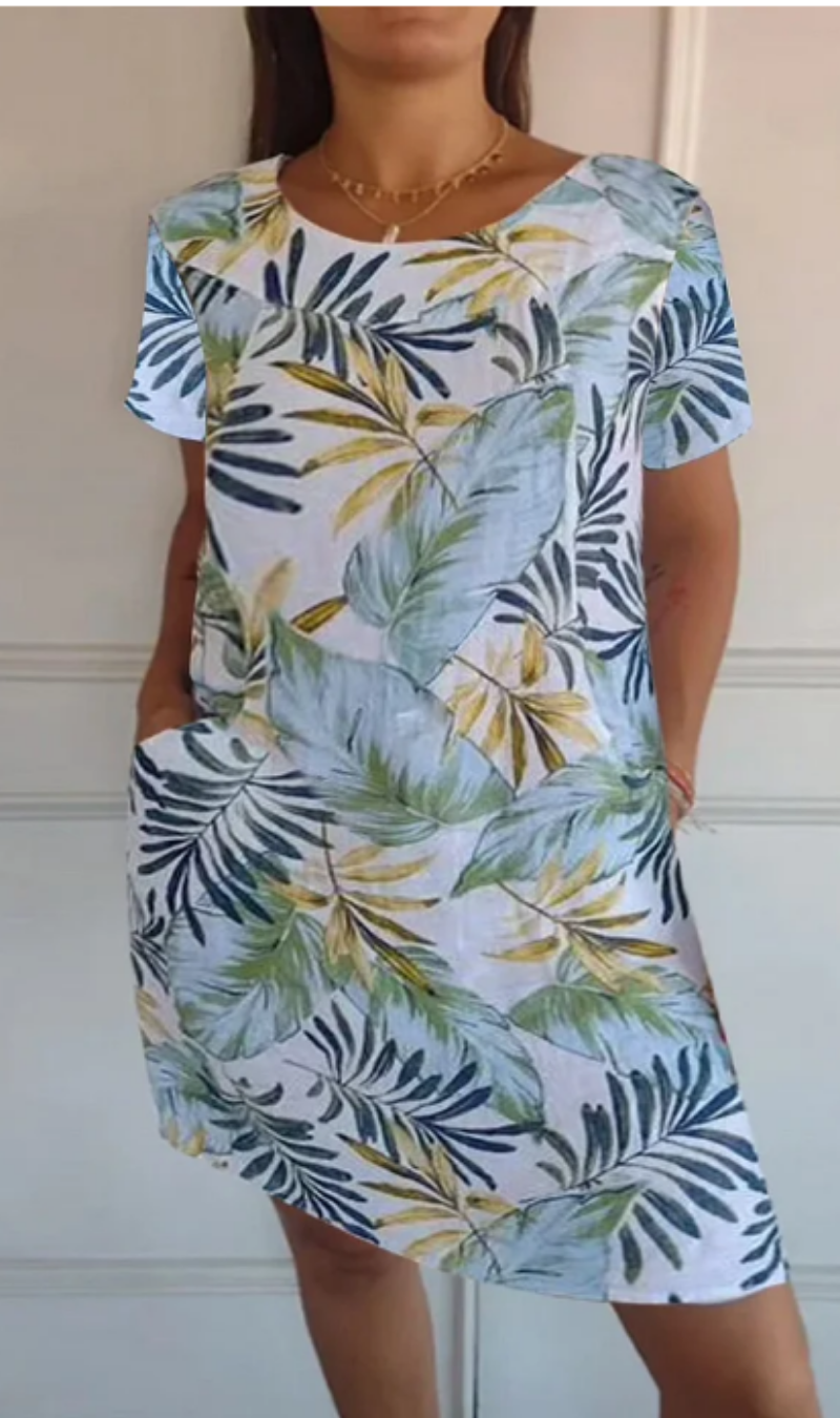 Primo piano della stampa botanica su abito fluido donna, con accenno alle tasche.
