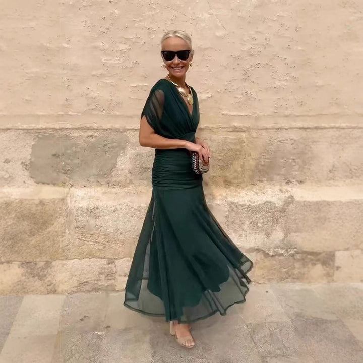 Abito cocktail nero con maniche trasparenti, scollo a V e vestibilità aderente per un look chic.