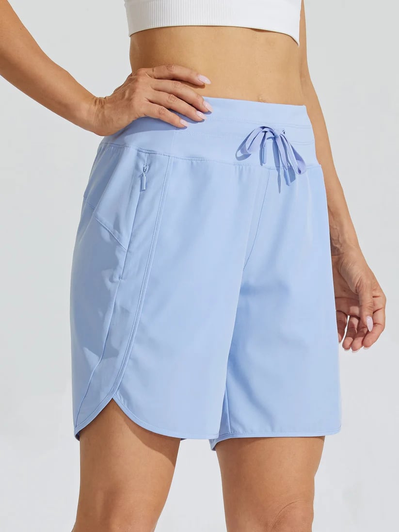 Modella indossa shorts sportivi donna vita alta blu scuro per attività fisica, con tasche laterali pratiche.