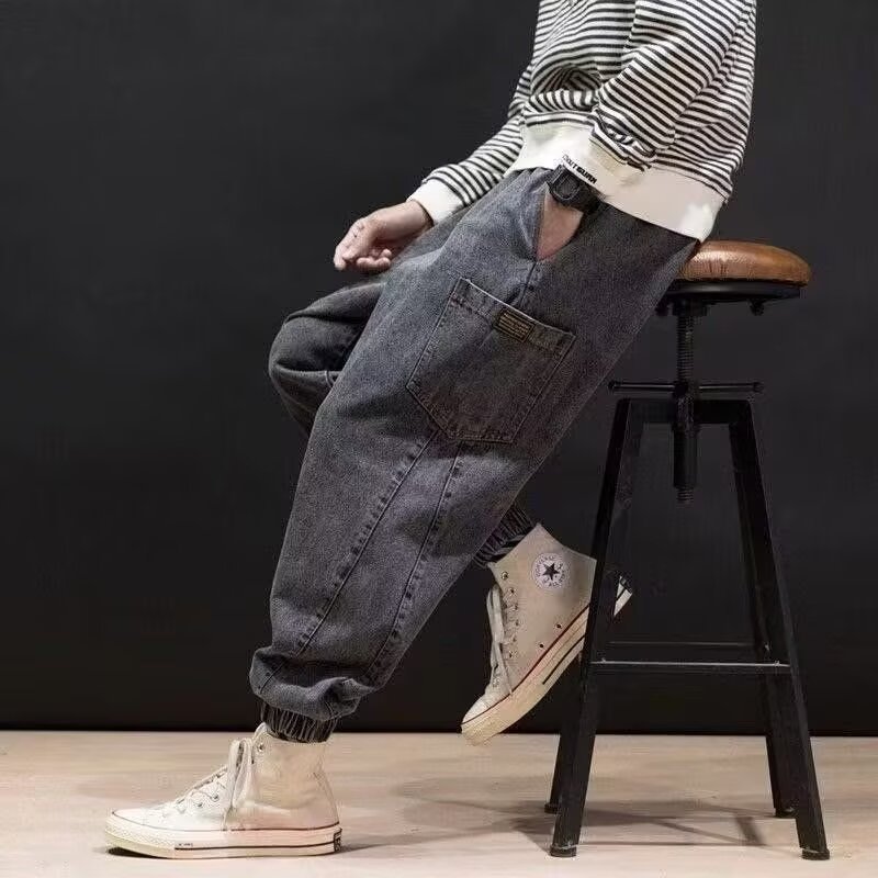 Uomo indossa jeans ricamati relaxed fit blu navy a vita media, ideali per un outfit urbano contemporaneo e comodo.