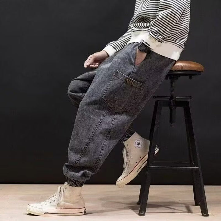 Uomo indossa jeans ricamati relaxed fit blu navy a vita media, ideali per un outfit urbano contemporaneo e comodo.