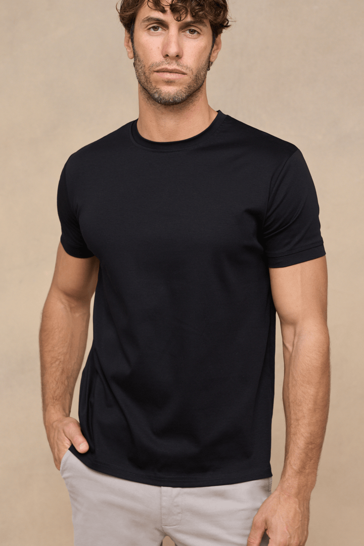 Uomo con t-shirt nera girocollo, morbida e confortevole, ideale per un outfit casual quotidiano. Abbigliamento maschile versatile.