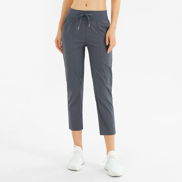 Pantaloni sportivi donna a nove decimi, vita media con tasche, perfetti per yoga e allenamento.
