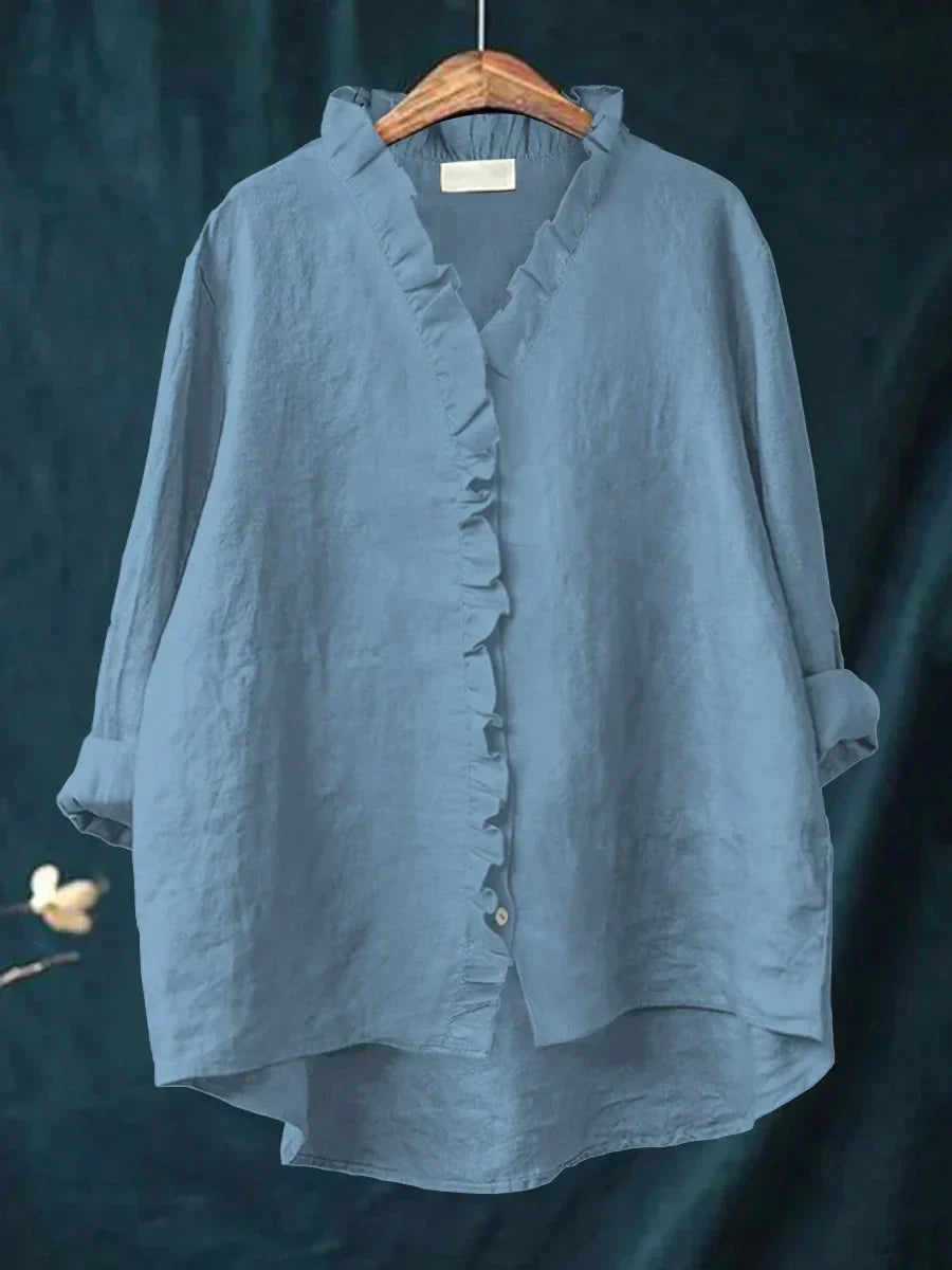 Dettaglio ravvicinato della camicia in lino da donna, con bottoni madreperlati e delicati volant.