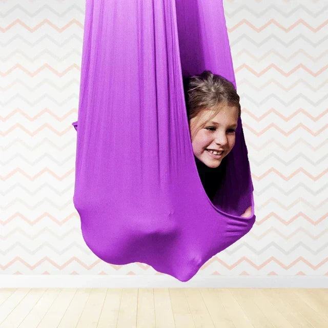 Bambino sereno sull'altalena terapeutica sensoriale. Un dondolo rilassante per divertimento, calma e sviluppo.