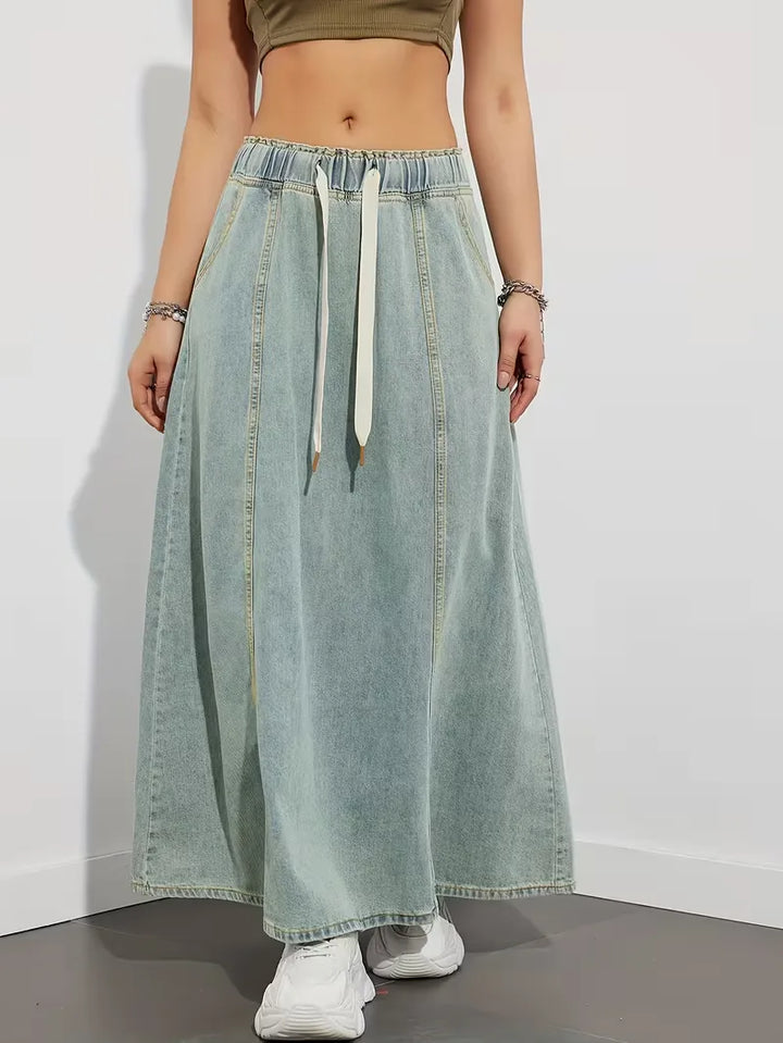 Donna che indossa una gonna maxi in denim azzurro con vita elasticizzata, stile casual e moderno.