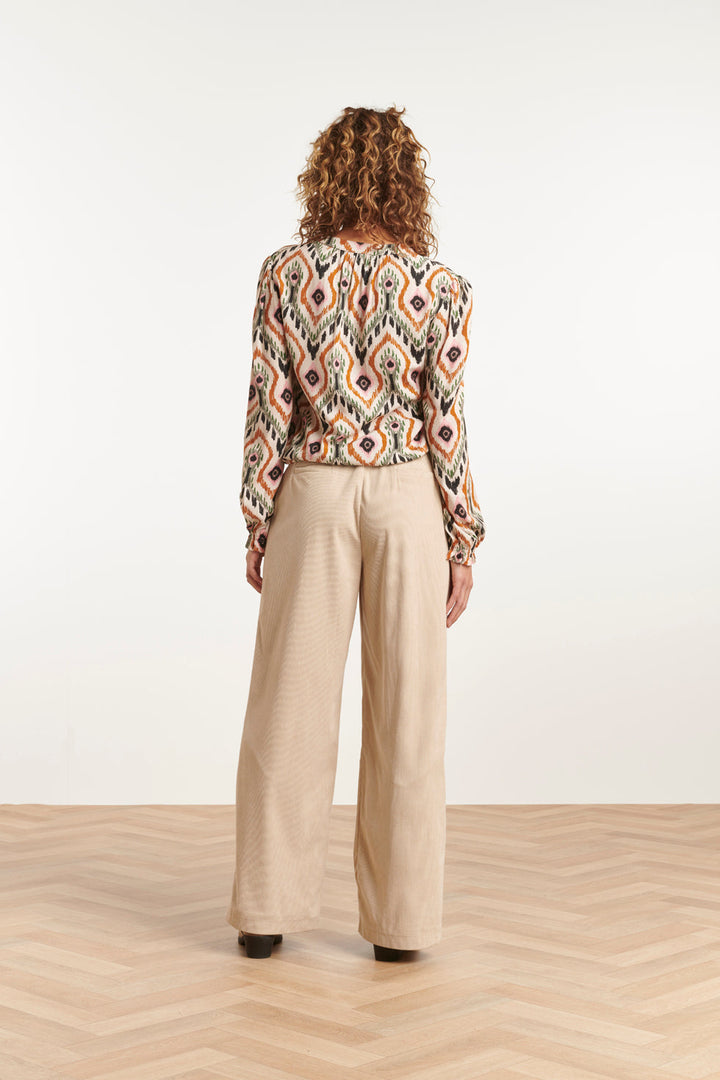 Top donna con scollo a V e maniche lunghe, taglio ampio e lunghezza corta. Stampa tribale in tonalità beige rosato.