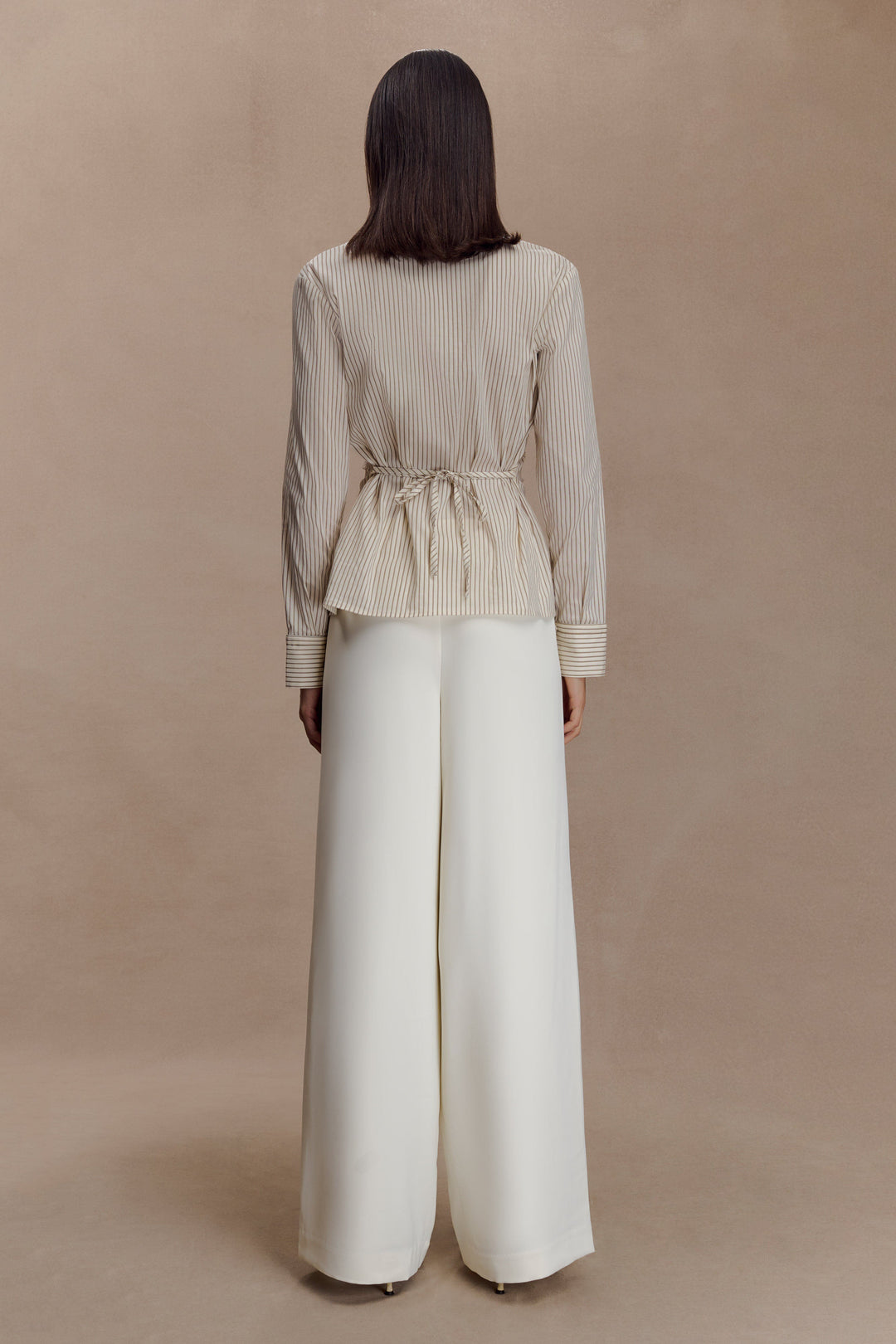Dettaglio camicia donna beige, righe sottili verticali, vita arricciata. Un capo chic per ogni occasione.