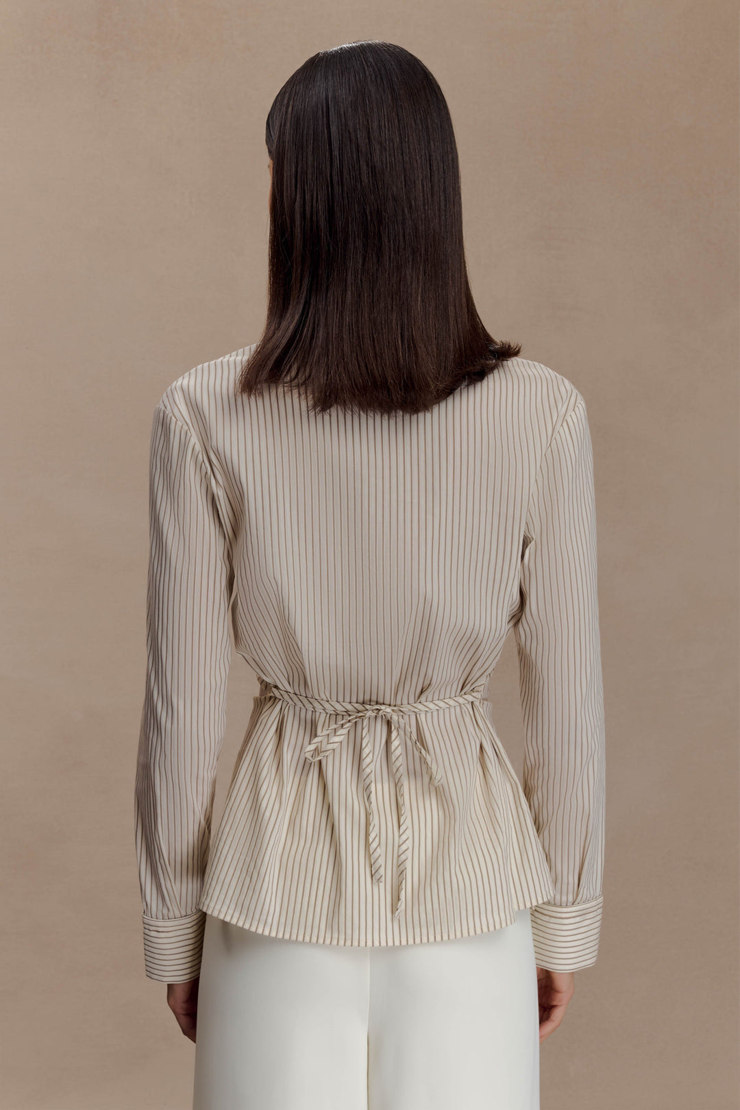 Camicia donna beige con vita arricciata e righe sottili, maniche lunghe. Perfetta per eleganza ufficio.