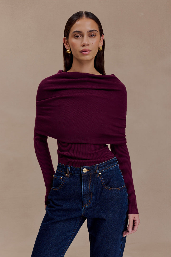Top donna bordeaux con scollo asimmetrico che scopre una spalla, collo alto. Pullover elegante e alla moda.