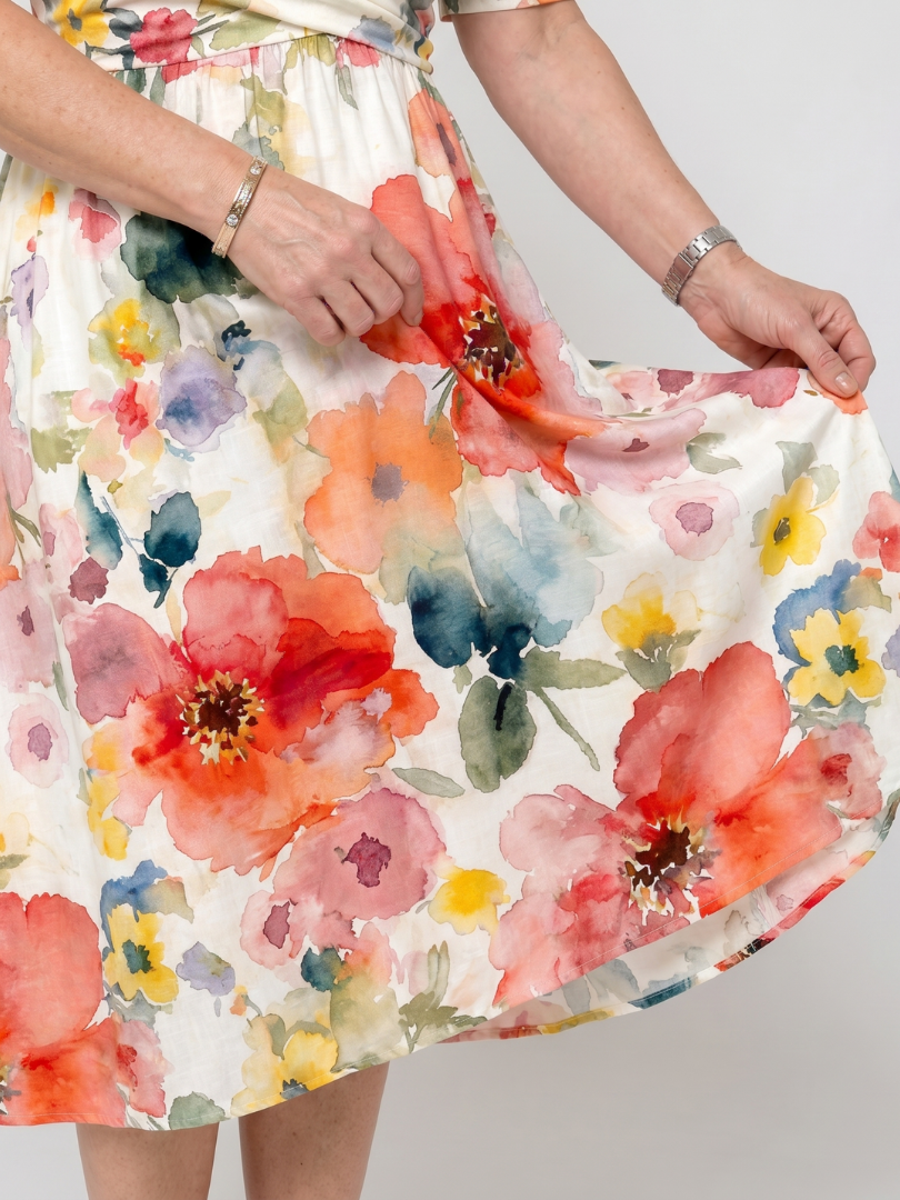 Vestito da donna midi con vivaci fiori, scollo a V profondo e maniche corte. Stile leggero e femminile.