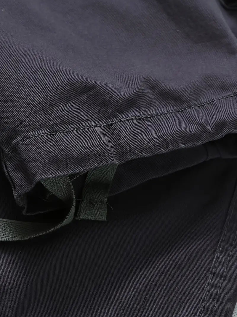 Dettaglio ravvicinato di tessuto e tasche funzionali sui pantaloni cargo uomo, ideali per l'avventura.
