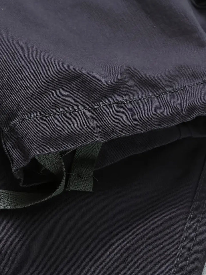 Dettaglio ravvicinato di tessuto e tasche funzionali sui pantaloni cargo uomo, ideali per l'avventura.