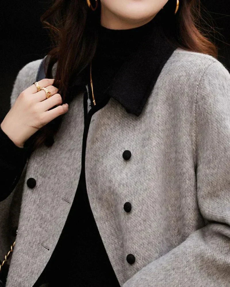 Cappotto lungo da donna grigio, con bottoni e dettagli a contrasto. Ideale per un look elegante e invernale.