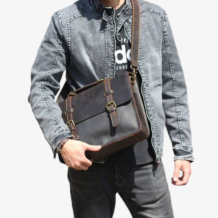 Borsa messenger unisex marrone scuro con patta robusta e fibbie, tracolla regolabile, accessorio versatile.