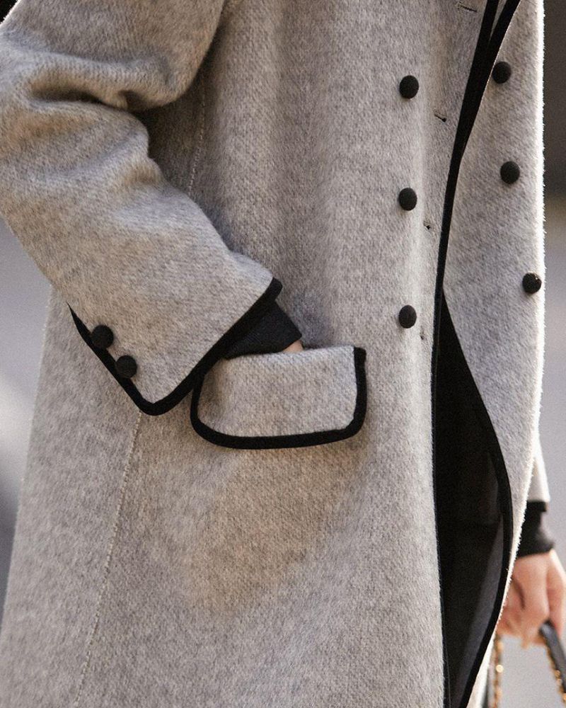 Moda donna: cappotto invernale elegante grigio, lungo con bottoni e dettagli a contrasto. Stile classico.