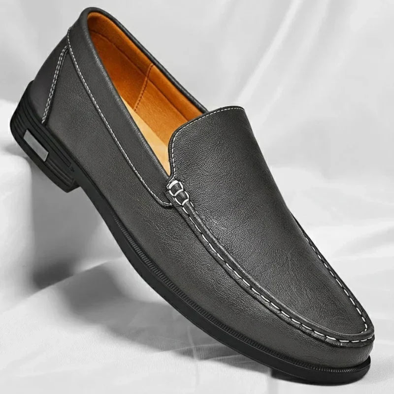 Dettaglio frontale mocassino uomo in pelle con cuciture a contrasto e morsetto decorativo. Scarpa elegante slip-on.