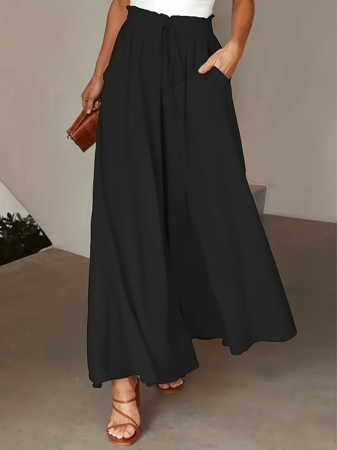 Donna che indossa pantaloni palazzo neri a vita alta, stile boho ed eleganza casual.