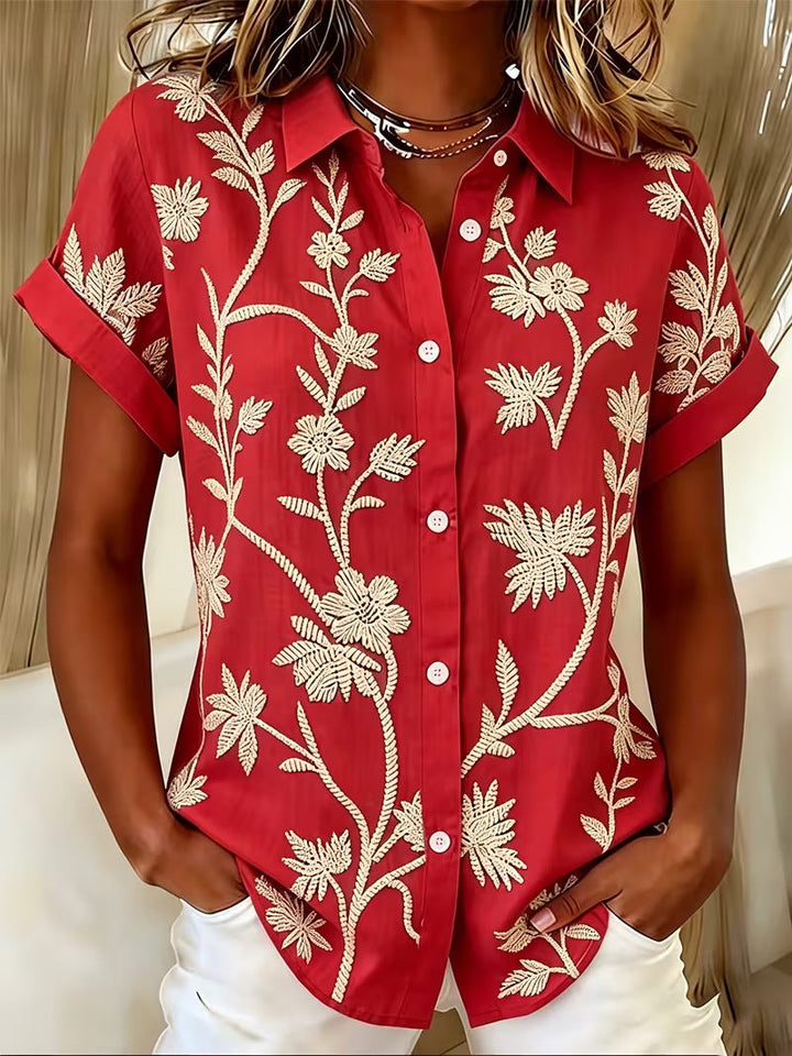 Top elegante donna, blusa floreale a maniche corte per abbigliamento estivo. Stile moderno e raffinato.
