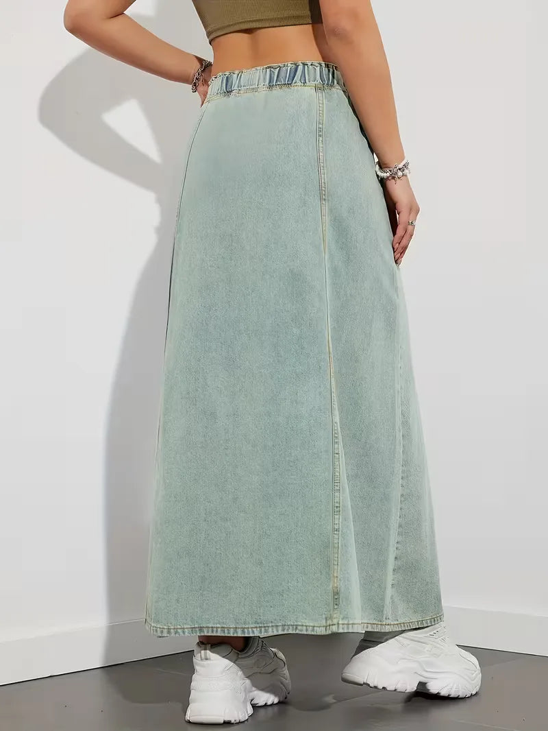 Donna cammina indossando gonna maxi denim blu, vita elasticizzata, stile comodo e casual per il giorno.