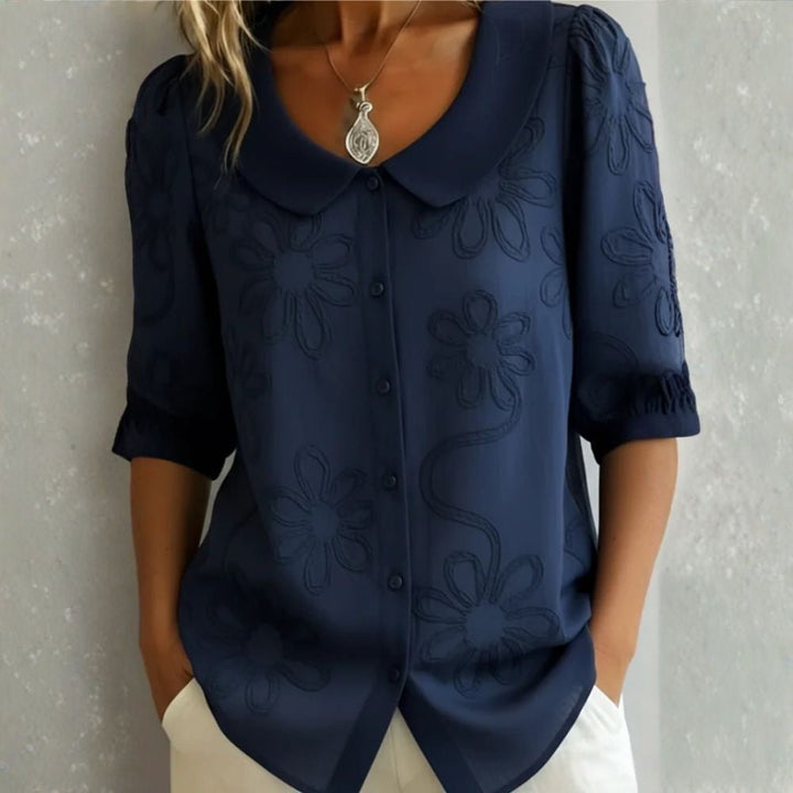 Camicetta elegante da donna con delicati dettagli floreali e colletto arrotondato. Stile raffinato.