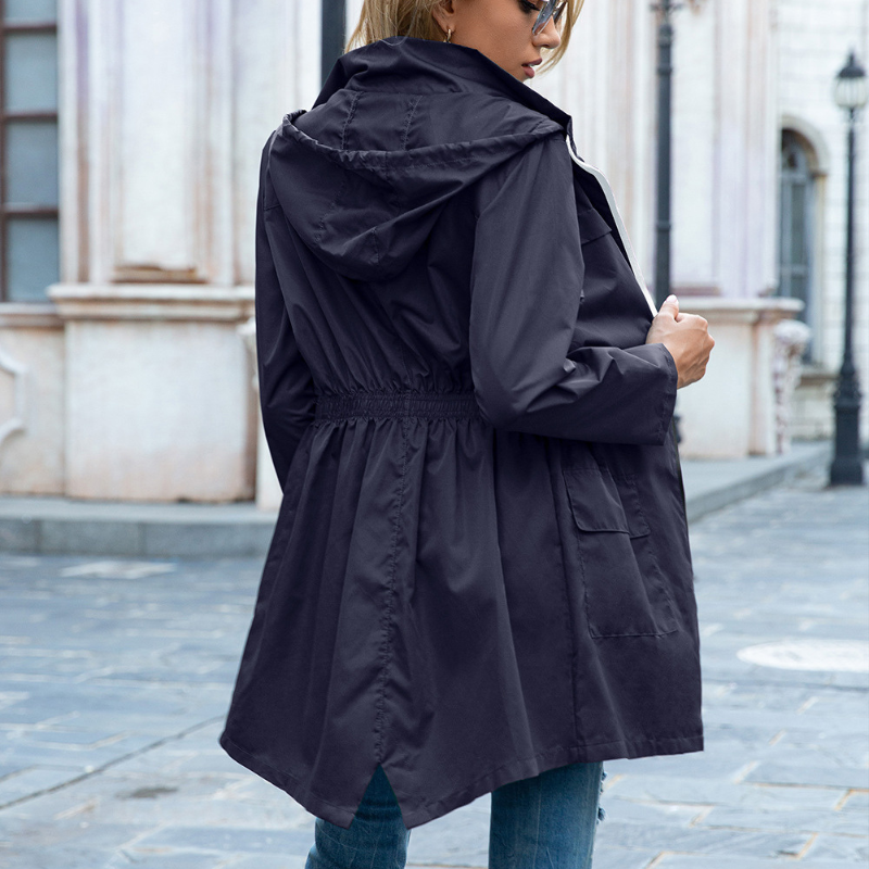 Donna indossa parka impermeabile chic in città, passeggiata sotto la pioggia. Giacca elegante e funzionale da donna.