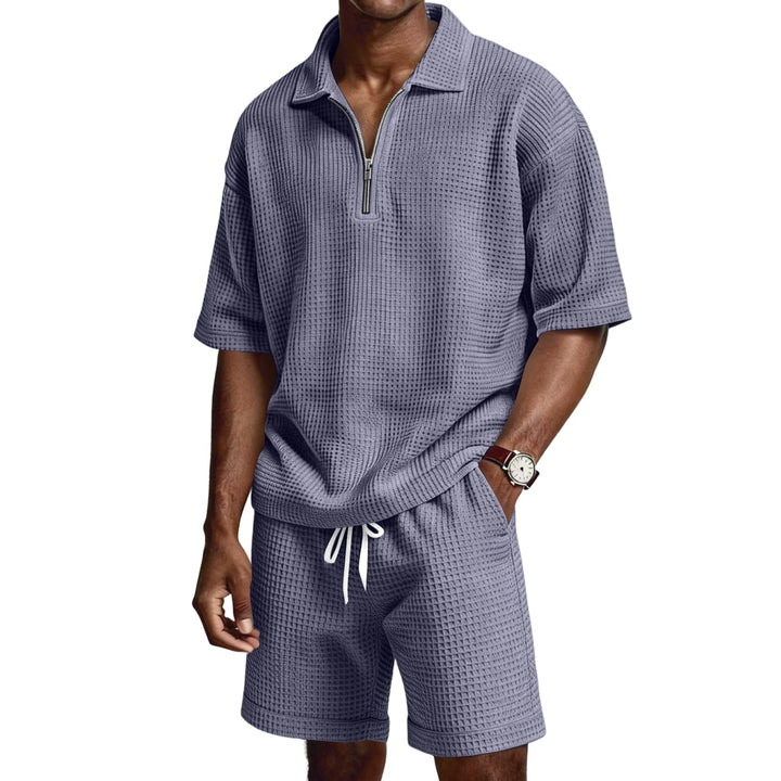 Completo uomo estivo due pezzi, con polo a zip e pantaloncini. Abbigliamento casual per la stagione calda.