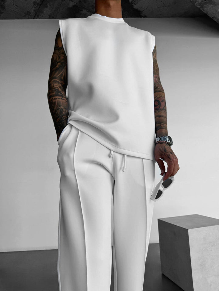 Set lounge moderno uomo, top sleeveless e pantaloni sartoriali, ideale per un look da giorno confortevole.