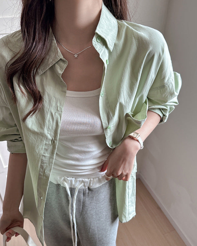 Moderna camicia bianca lunga da donna, tinta unita e vestibilità comoda oversize.