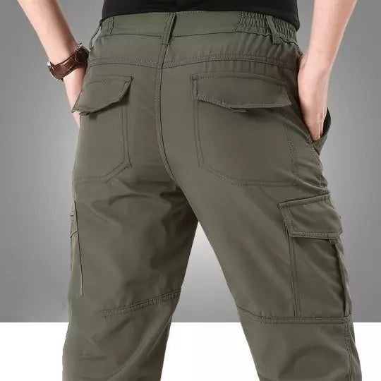 Uomo inginocchiato con pantaloni tattici, dimostrando flessibilità e resistenza.