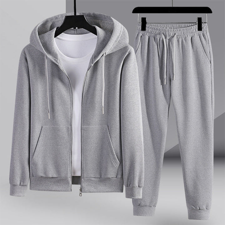 Set sportivo uomo moderno: felpa con cappuccio e pantaloni in tessuto nido d'ape per un look casual e confortevole.