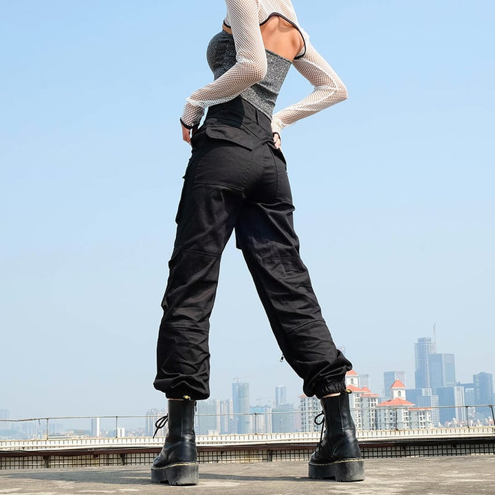 Donna indossa pantaloni cargo neri a vita alta con polsini. Stile streetwear casual per un look urbano e di tendenza.