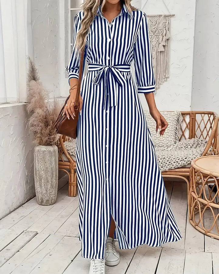 Abito camicia donna a righe blu e bianche con colletto a rever e bottoni frontali, perfetto per look casual o ufficio.
