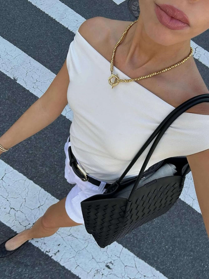 Donna con borsa tote intrecciata, accessorio moda capiente che completa il look quotidiano.