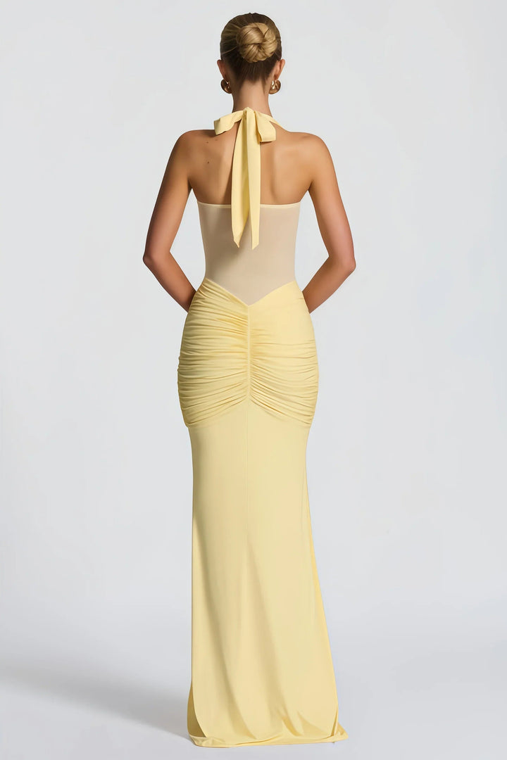Dettaglio drappeggio a nodo su abito lungo giallo donna con collo halter, stile sirena aderente.