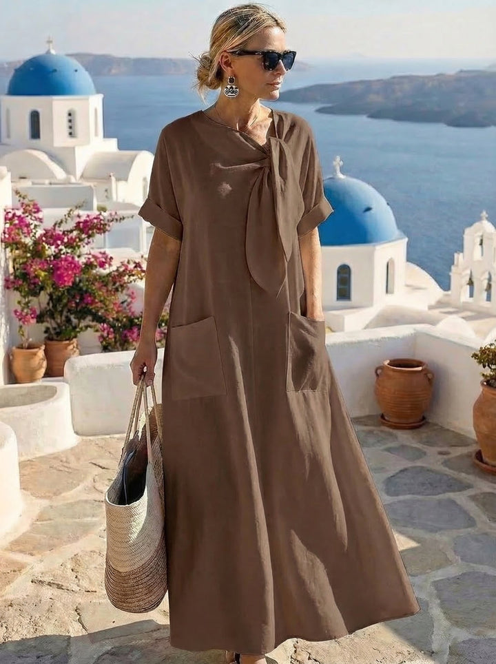 Abito lungo donna, stile maxi con nodo frontale decorativo e pratiche ampie tasche laterali.