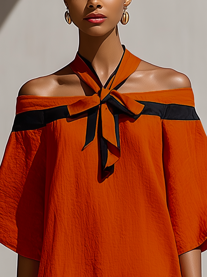 Dettaglio fiocco su mini abito terracotta off-shoulder con maniche balloon. Eleganza e moda donna per la sera.