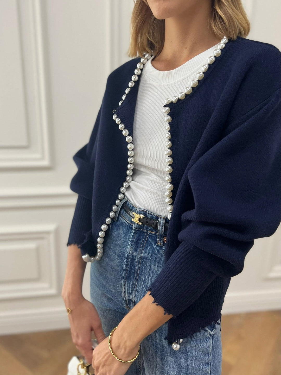 Primo piano: texture e perle su cardigan donna elegante. Maglia a maniche lunghe, tocco di classe.