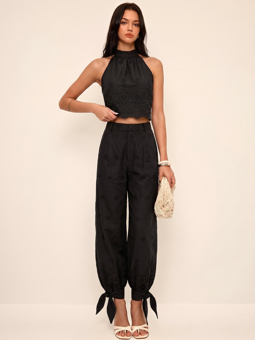 Moda donna due pezzi elegante: top corto traforato e pantaloni fluidi con laccetti, perfetto per un look primaverile.