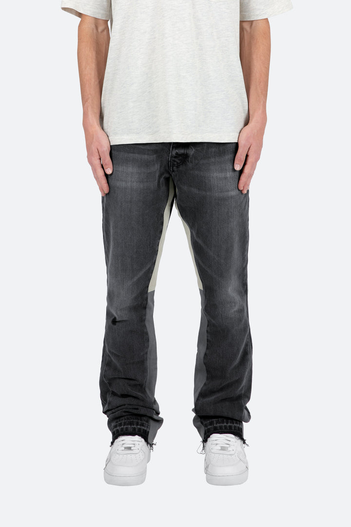 Jeans a zampa uomo neri con lavaggio sfumato, vestibilità aderente e fondo svasato. Moda maschile di tendenza.