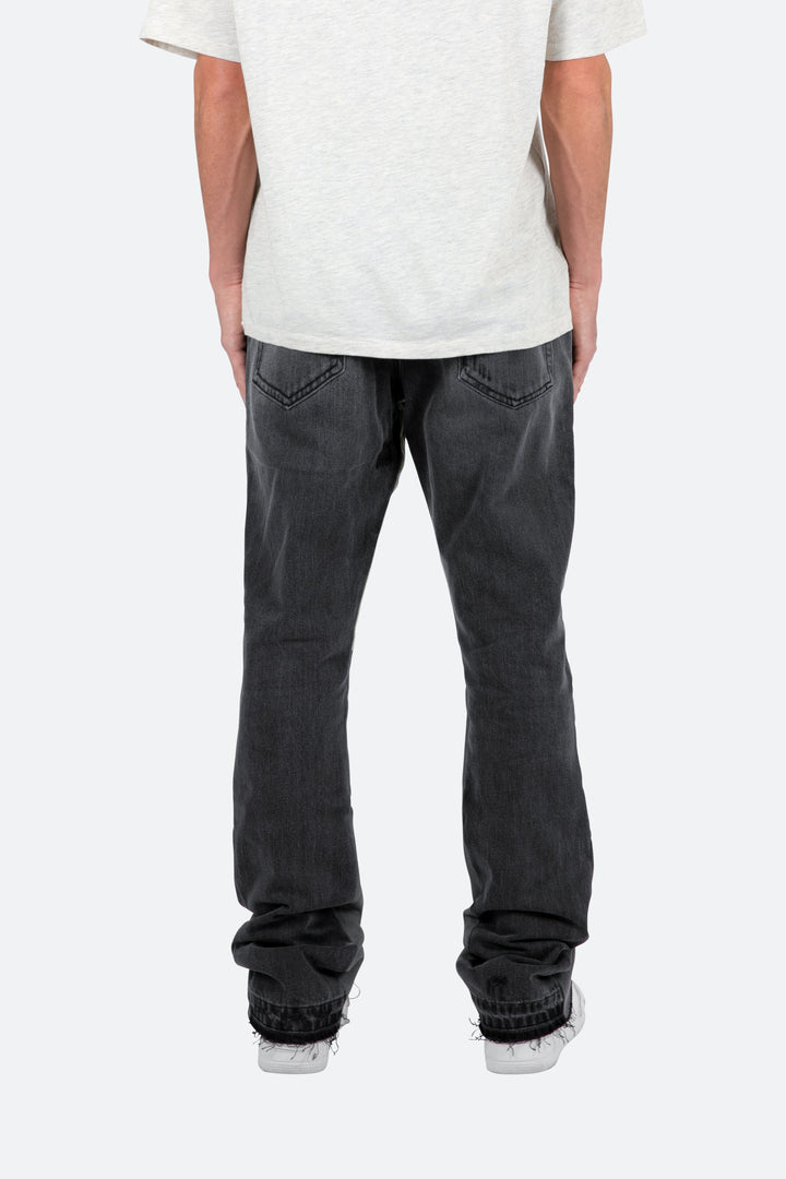 Pantaloni denim neri sfumati, vestibilità slim e fondo svasato. Jeans uomo a zampa per stile contemporaneo.