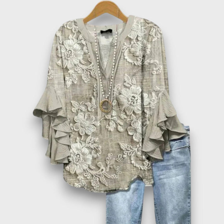 Dettaglio camicetta donna elegante con volant, scollo a V e lacci. Texture leggera, ideale per l'estate.