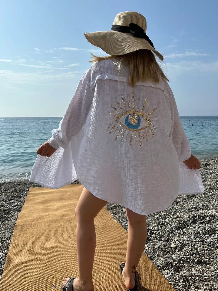 Camicia oversize donna bianca con ricamo occhio e paillettes scintillanti. Comoda e versatile per ogni occasione estiva.