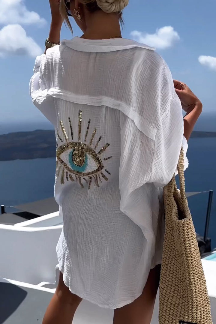 Camicia oversize donna con ricamo occhio e paillettes dorate. Perfetta per look estivi chic e casual.