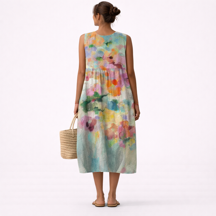 Donna indossa abito midi smanicato con stampa acquerello vivace e unica. Vestito fluido e confortevole per l'estate.